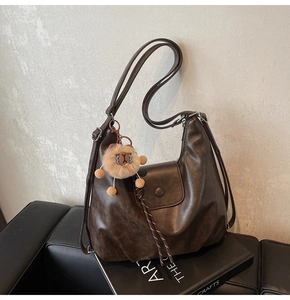 Close-up of dark brown hobo bag in soft synthetic leather with a cute plush lion charm