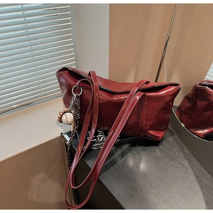 Detail of red glossy patent leather tote bag with creative baseball glove charm