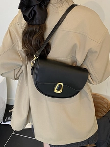 Minimalist black matte leather saddle bag with golden U-shaped buckle on a model
