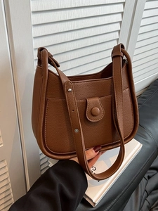 Minimalist brown litchi pattern leather bucket bag with an adjustable shoulder strap