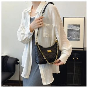 Detail of black quilted leather shoulder bag featuring gold chain and metallic buckle