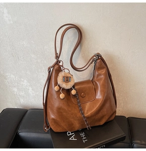 Close-up of brown vintage PU leather hobo bag with front snap pocket and plush charm