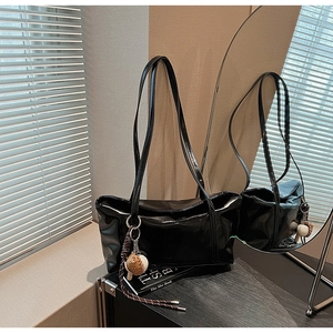 Detail of glossy black patent leather tote bag with a unique baseball theme charm accessory