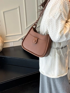 Brown half-moon shoulder bag with pebble grain texture and adjustable metal buckle