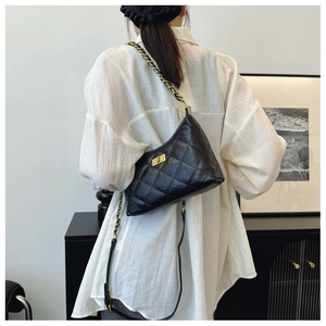 Detail of black quilted dumpling bag featuring golden chain strap and metallic twist lock