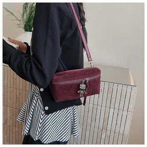 Detail view of burgundy suede crossbody bag with silver robot charm and metal zipper