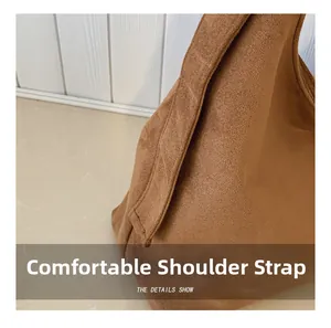 Detail view of the wide shoulder strap and premium matte suede texture on a brown tote bag