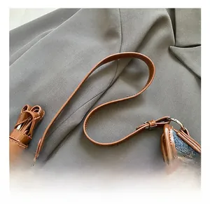 Detail of blue denim hobo bag showing brown leather handle and silver metal hardware