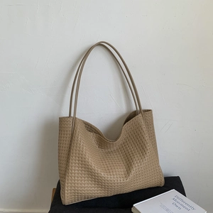 Détail de la texture en cuir PU tressé kaki et de la bandoulière sur un grand sac cabas