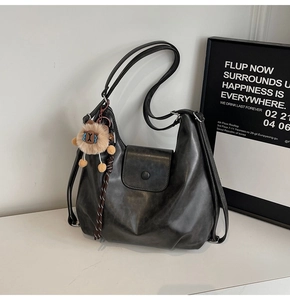 Detail view of large black retro tote bag with matte leather and lion charm accessory