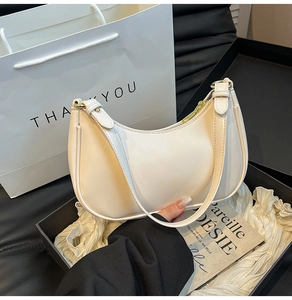 Detailed close-up of cream half-moon shoulder bag in elegant gift packaging box
