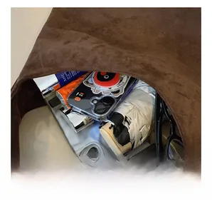 Macro view showing large capacity interior of dark brown suede tote bag with daily items