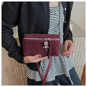 Detail of burgundy suede camera bag featuring a unique silver robot pendant on the zipper