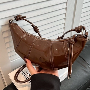 Fashionable dark brown patent leather croissant bag with stylish knot details and shiny finish
