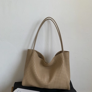 Détail d'un grand sac cabas tressé kaki montrant la texture du cuir et sa contenance