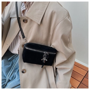 Close-up of black suede crossbody bag featuring a unique silver robot metal charm
