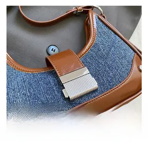 Detailed close-up of the vintage silver metal buckle on the blue denim and brown leather bag