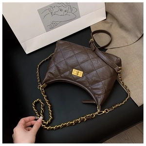 Detail of dark brown quilted hobo bag featuring golden metal twist lock and chain strap