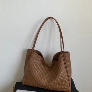 Détail d'un grand sac cabas tissé marron foncé avec une texture rétro et minimaliste
