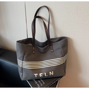 Detail view of charcoal gray canvas tote bag with white stripes and brown handles