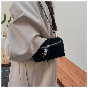 Detail shot of black suede shoulder bag featuring a unique silver robot metal charm