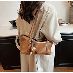 Brown glossy leather tote bag with braided charm detail on shoulder for commuting