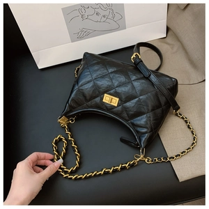 Close-up of quilted black dumpling bag with golden twist-lock and chain strap detail