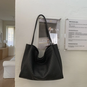 Gros plan détaillé d'un sac cabas en cuir tressé noir avec une texture à carreaux