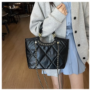Détail d'un sac à main noir matelassé avec chaîne dorée dans un cadre moderne