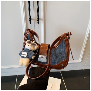 Detail of denim and brown leather handbag with vintage striped clasp and bear charm