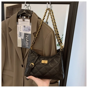 Close-up of black quilted dumpling bag with gold twist lock and chain strap details