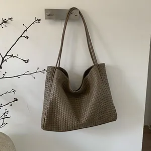 Gros plan sur la texture en cuir tressé marron d'un grand sac cabas à doubles bandoulières