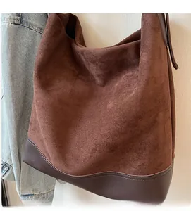 Detailed view of large brown suede tote bag texture with smooth leather base and stitching