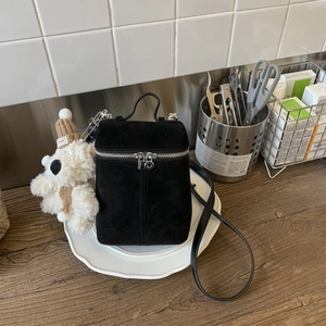 Details einer schwarzen Vintage-Wildledertasche mit einem süßen Teddybären-Anhänger
