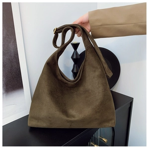 Detailed view of the dark suede hobo bag featuring a wide strap and gold hardware buckle