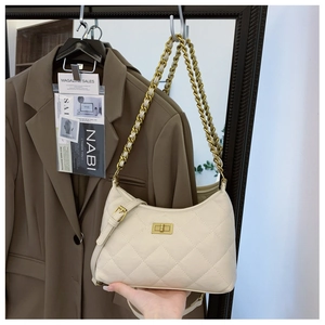 Detail of white quilted handbag with golden twist lock and elegant chain shoulder strap
