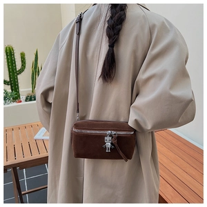 Detail of vintage brown suede crossbody bag featuring a silver robot zipper pendant charm