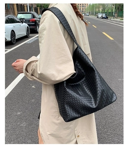 Detailed street style shot of the large black woven leather hobo bag and strap texture