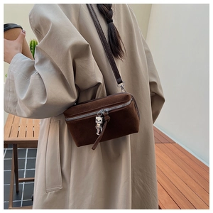 Detail view of suede crossbody bag with silver zipper and unique robot charm accessory