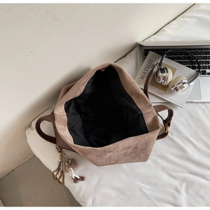 Top-down view of large brown leather tote bag with plush charm and spacious interior