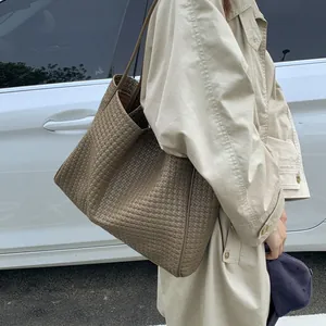 Détail d'un grand sac cabas en cuir tressé marron café porté par un mannequin en extérieur