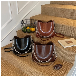 Three retro bucket bags in black and brown with chunky silver chains on stairs