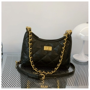 Close-up of black quilted leather dumpling bag with gold chain strap and turn-lock