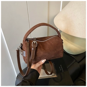 Dettaglio borsa a cilindro in camoscio marrone con finiture in pelle e zip argento