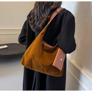 Detailed view of brown suede hobo tote bag with matching coin pouch worn by a model