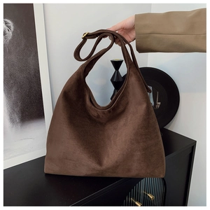 Detail of a large brown suede tote bag with adjustable strap and gold metal buckle