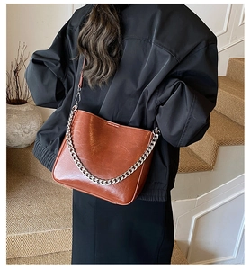 Detail view of caramel brown leather bucket bag with silver metal chain and shoulder strap