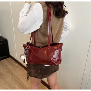 Detail view of large dark red glossy leather shoulder bag with creative baseball charm