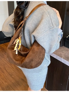 Braune Wildleder-Schultertasche mit Holzperlen-Quaste an einem Model präsentiert