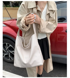 Outdoor street style view of woman wearing large off-white woven hobo shoulder bag